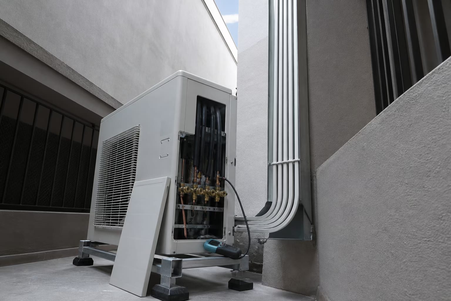 Unidad exterior multisplit en un patio interior con seis líneas frigoríficas aisladas subiendo canalizadas por la pared.