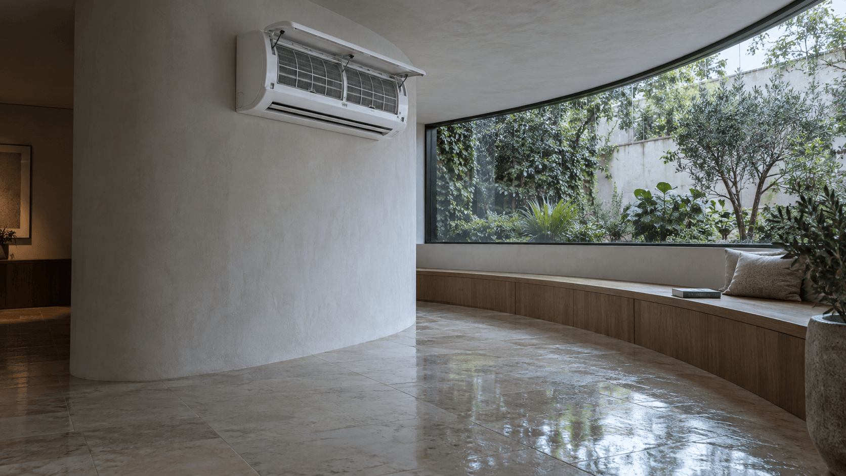 Mantenimiento de aire acondicionado en Boadilla del Monte — Split mural completo con el panel abierto y los filtros visibles en una galería curva junto a un jardín — Mitsutec